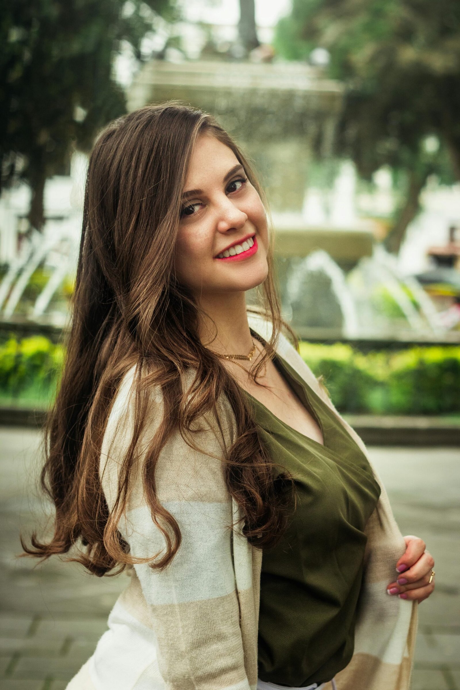 A cheerful woman with red lips and long hair enjoys a sunny day in an Ibarra park.